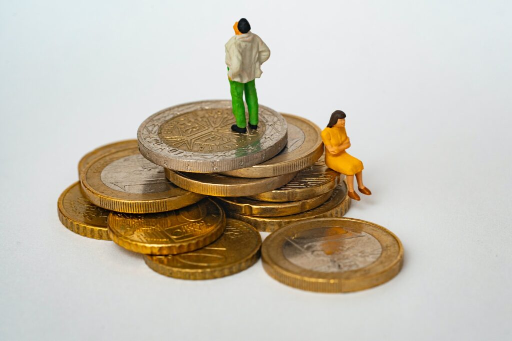 two tiny figurines standing on coins